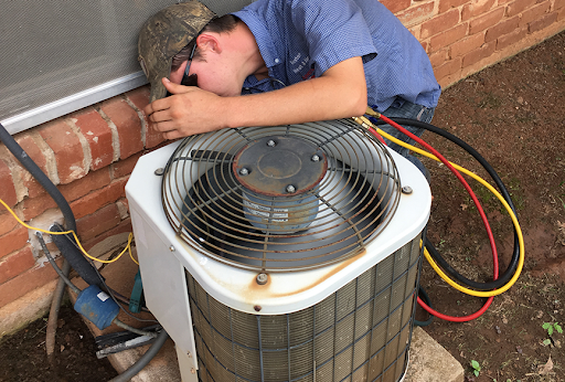 Elmore City HVAC technician repairing air conditioner outside of home